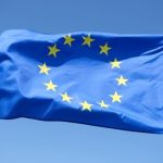 Прапор ЄС поряд із символічним зображенням санкційного пакета