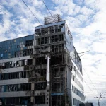 Пошкоджений фасад бізнес-центру «Інком» і горівші автівки на парковці після удару БпЛА в Солом'янському районі Києва