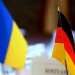Громадяни Німеччини біля символіки ЄС на тлі прапорів України та Німеччини