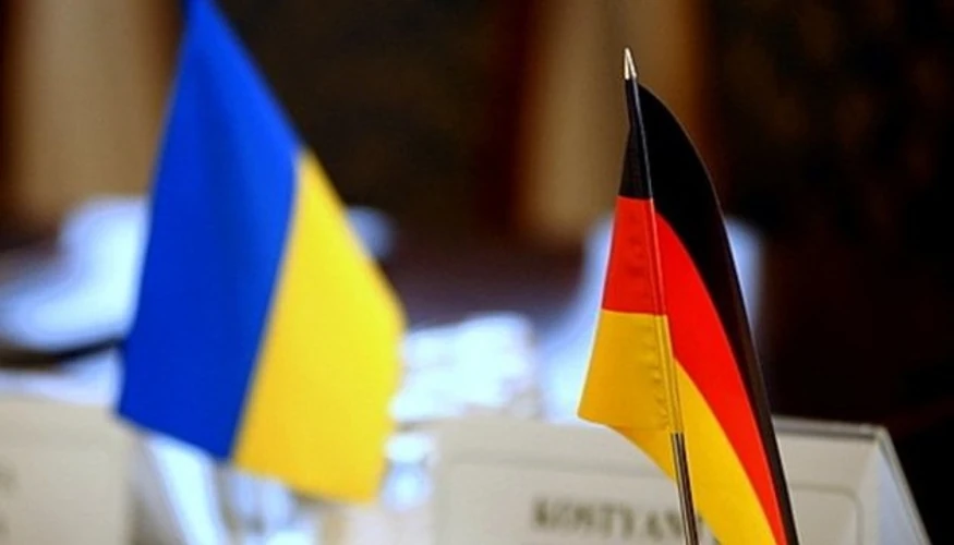 Громадяни Німеччини біля символіки ЄС на тлі прапорів України та Німеччини