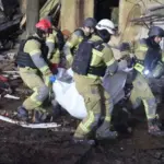 Рятувальники несуть тіло загиблої людини з-під завалів зруйнованого будинку у Холодногірському районі Харкова